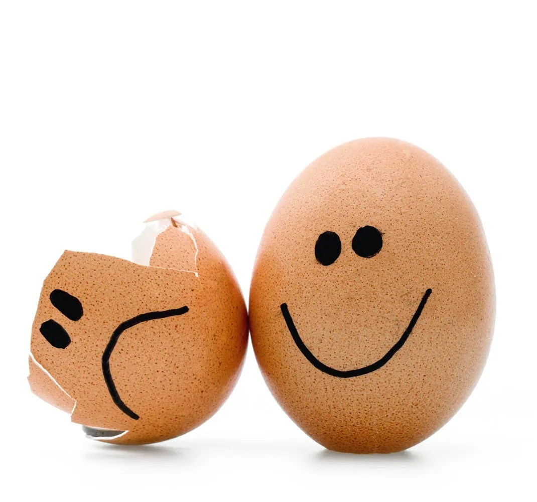 Zwei braune Eier, eines mit einem lächelnden Gesicht und das andere mit einer gebrochenen Schale und einem lächelnden Gesicht.